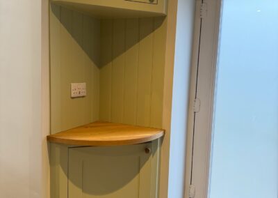 Green hallway storage with oak shelf
